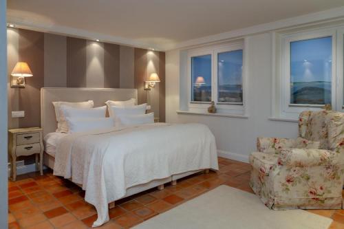 a bedroom with a bed and a chair and windows at Luxus Sönshörn 20 in Munkmarsch