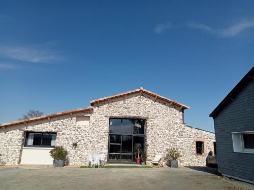 - un bâtiment en pierre avec deux chiens devant dans l'établissement Chambres d'hôtes LA GRANGE DU PA de LA GROLLE, à Rocheservière