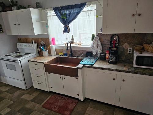 a kitchen with white cabinets and a sink and a stove at The Zen Den in Del Norte