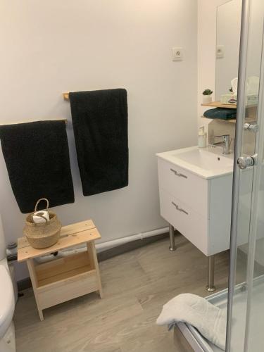 La salle de bains est pourvue de serviettes noires, d'un lavabo et d'une table. dans l'établissement Centre-Ville Parking Gratuit Proche Aéroport, à Beauvais