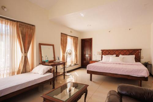 a hotel room with two beds and a couch at Maharshis Guddethota Homestay in Chikmagalur