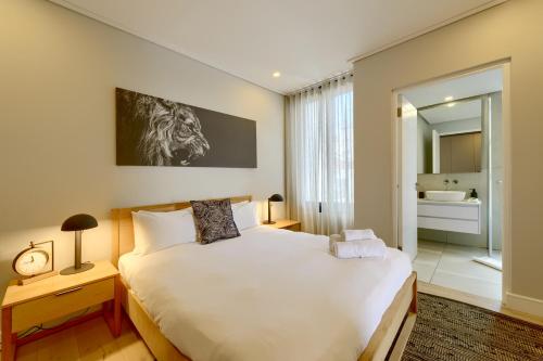 a bedroom with a large white bed and a bathroom at 7 on Bantry Luxury Residence 305 in Cape Town