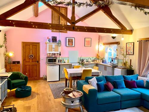 a living room with a blue couch and a kitchen at The Clock House Hideaway in Lamberhurst