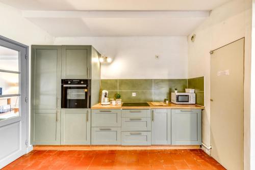 a kitchen with white cabinets and a microwave at L'Escapade - Parking Gratuit - WIFI - Climatisation - Proche Cité - Tout Equipée in Carcassonne