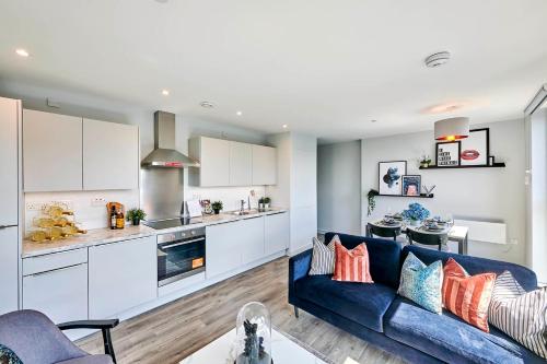 a living room with a blue couch and a kitchen at Duet Manchester in Manchester