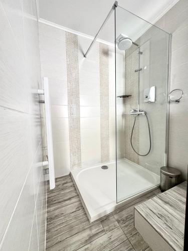 une salle de bain blanche avec une douche avec une porte vitrée dans l'établissement Hotel La Citadelle, à Villefranche-sur-Mer