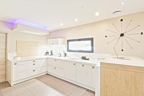 une cuisine avec des placards blancs et une grande horloge murale dans l'établissement Villa Levant Piscine et Calme, à Poulx
