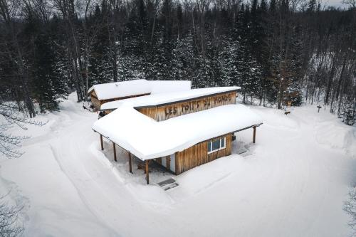 a cabin in the snow with snow on the roof at Les Toits Du Monde in Nominingue