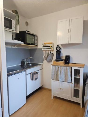 une petite cuisine avec des armoires blanches et un évier dans l'établissement Studio au pied des pistes refait à neuf, à Enchastrayes