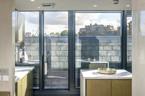 a kitchen with a large window with a view of a castle at The RÌGH Penthouse Suite in Edinburgh