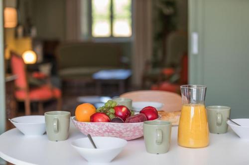 a table with a bowl of fruit and a glass of orange juice at Jouandeou in Donzacq