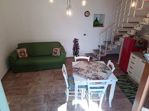 Una sala de estar con una mesa y sillas y un sofá verde. en Da Giorgia, en Forza dʼAgro