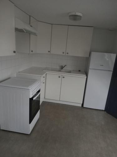 La cuisine est équipée de placards blancs, d'une cuisinière et d'un réfrigérateur. dans l'établissement STUDIO MEUBLE professionnel Fruges, à Fruges