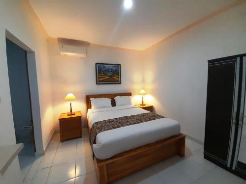 a bedroom with a bed and two lamps on tables at Pondok Dauh Ancak Kelating Guest House in Krambitan