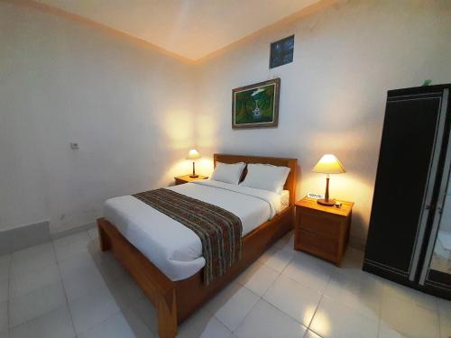 a bedroom with a bed and two night stands with lamps at Pondok Dauh Ancak Kelating Guest House in Krambitan
