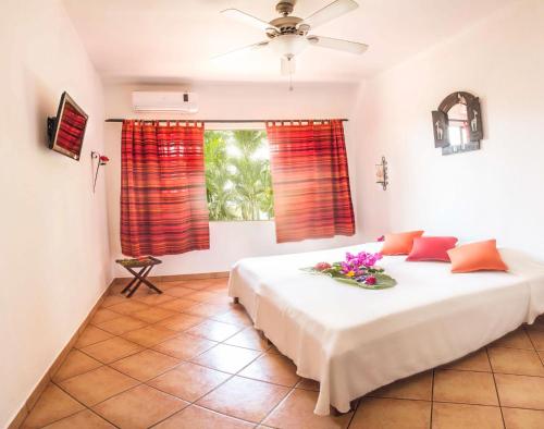 a bedroom with a large white bed with red curtains at Hotel Laguna del Cocodrilo in Tamarindo