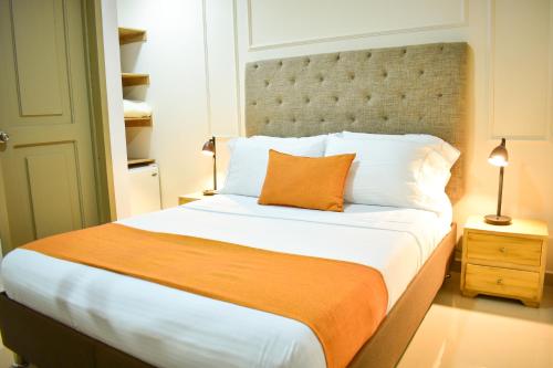 a bedroom with a large bed with an orange pillow at Hotel Cafe Cafe Avenida in Armenia