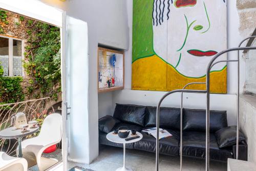 a living room with a couch and tables and a painting at Palais Aoma, hôtel particulier de luxe en Provence in LʼIsle-sur-la-Sorgue