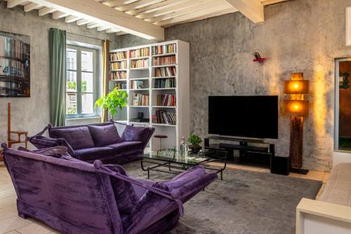 a living room with purple furniture and a tv at Palais Aoma, hôtel particulier de luxe en Provence in LʼIsle-sur-la-Sorgue