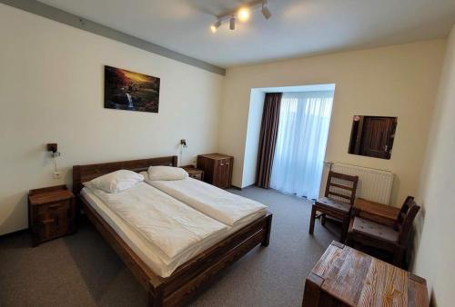 une chambre avec un lit, une table et une chaise dans l'établissement Pensiunea Eden Éden Panzió, à Odorheiu Secuiesc