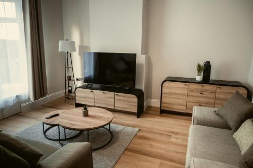 a living room with a flat screen tv and a coffee table at George Florence House in Spennymoor