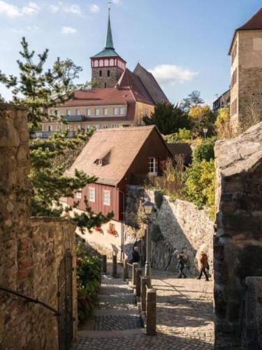 a village with a red building and a church at Wohnung In Niedergurig Mit Grill, Sauna Und Garten in Malschwitz