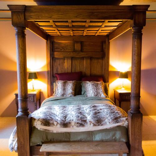 une chambre avec un lit en bois avec deux lampes dans l'établissement Commanderie des Champs Forts, à Saint-Aoustrille