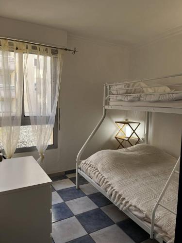 - une chambre avec des lits superposés et un sol en damier dans l'établissement Appartement T2 à 50 m de la plage, proche des commodités, à Canet