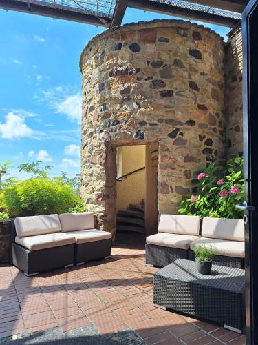 a patio with two couches in front of a stone building at Hotel Stadt Breisach in Breisach am Rhein