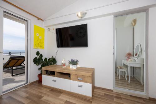 a living room with a tv and a sliding glass door at Apartman Štorija in Brela