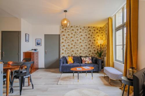 un salon avec un canapé bleu et une table dans l'établissement Le Cinq, Appartement de charme Place Saint Pierre Saumur, à Saumur