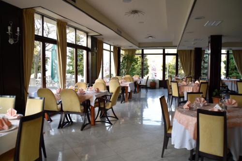 a dining room with tables and chairs and windows at Hotel Millennium in Pogradec