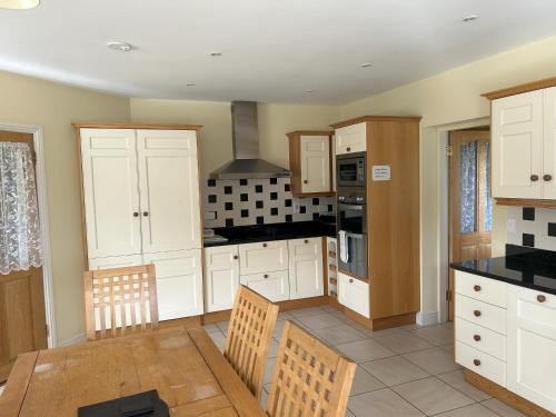 a kitchen with white cabinets and a table and chairs at Number 7 Bank House in Schull