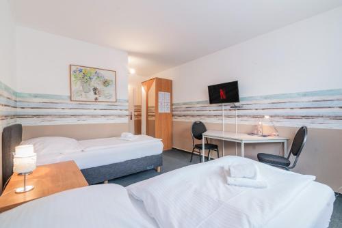 a hotel room with two beds and a desk at Hotel Café Galerie I Hannover-Garbsen I Free Parking in Garbsen