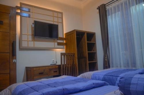 a bedroom with two beds and a flat screen tv at Casa De Leren in Ngabean
