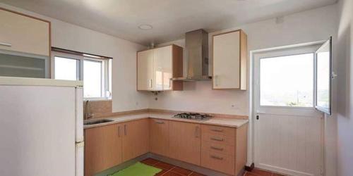 an empty kitchen with wooden cabinets and a window at Ericeira Dream Stay in Ericeira