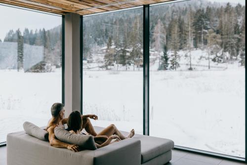 two people sitting on a couch looking out a window at Hotel Seespitz Superior - Adults Only in Seefeld in Tirol