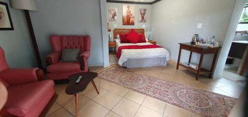 a bedroom with a bed and a chair and a table at Goggas Nest BNB & Restaurant in Matsapha
