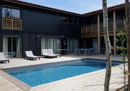 une piscine avec deux chaises et une maison dans l'établissement La Cabane de Chacha, à Lège-Cap-Ferret