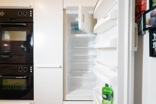 an open refrigerator with its door open and a refrigerator at Apartment Mariahalden in Weesen