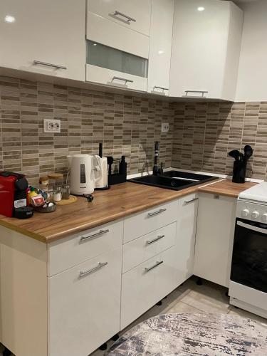 a kitchen with white cabinets and a sink at nani apartman in Vecsés