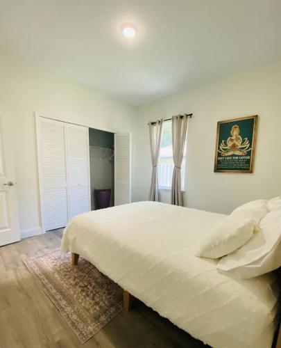 a white bedroom with a large bed and a window at Nirvana Nature's Nook in Palm Coast