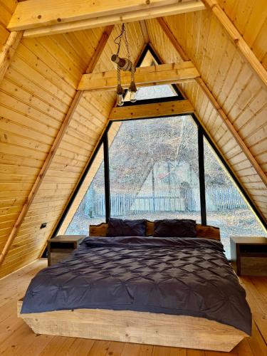 a bed in a room with a large window at Codrii Doftanei in Teşila