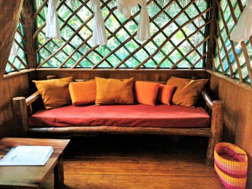 a red couch in a wooden room with a window at El Hotelito Perdido in Rio Dulce