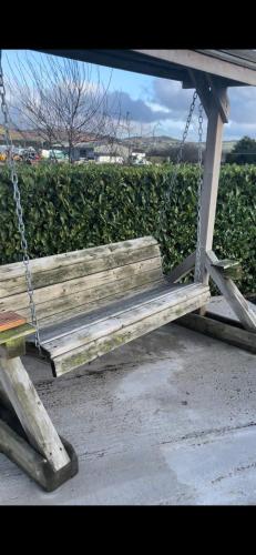 a wooden swing sitting in front of a bush at 1 Gullion Lodge Newry in Newry