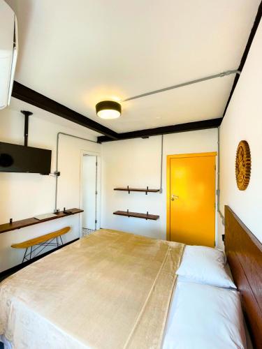 a large bed in a room with a yellow door at Laika Hostel in Camburi