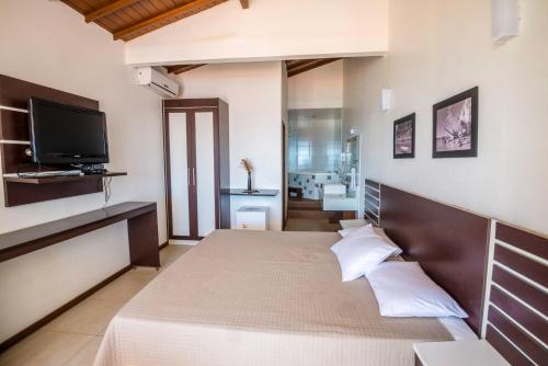 a bedroom with a bed with a tv on the wall at Pousada Ilha da Saudade in Morro de São Paulo