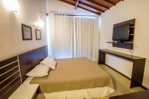 a bedroom with a bed and a flat screen tv at Pousada Ilha da Saudade in Morro de São Paulo
