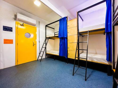a room with two bunk beds and a yellow door at Laika Hostel in Camburi