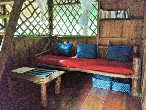 a red couch with blue pillows in a room at El Hotelito Perdido in Rio Dulce